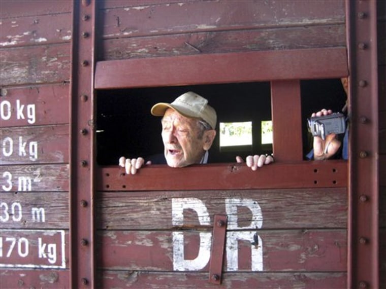 Holocaust survivor Adolek Kohn looks out the window of a train freight car that used to transport people to the Auschwitz death camp in Poland, in this undated image taken during the making of a clip in which he is dancing with his family on what easily could have been his own grave. The 4 1/2-minute clip of Adolek Kohn and his loved ones stiffly shuffling and shimmying to the disco hit, \"I Will Survive,\" at Auschwitz and other places where millions died during the Holocaust has become a surprise hit on YouTube, sparking a fierce debate over whether it disrespects those who perished or is an exuberant celebration of life.(AP Photo/Jane Korman)